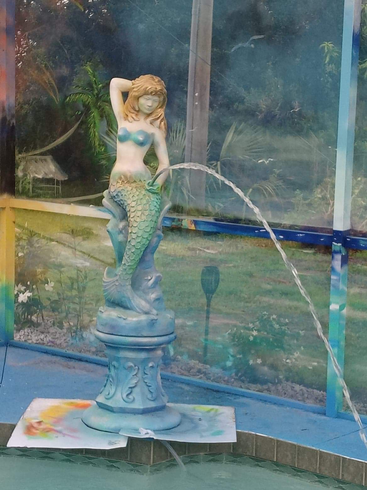 Finished mermaid fountain statue with painted base by the pool